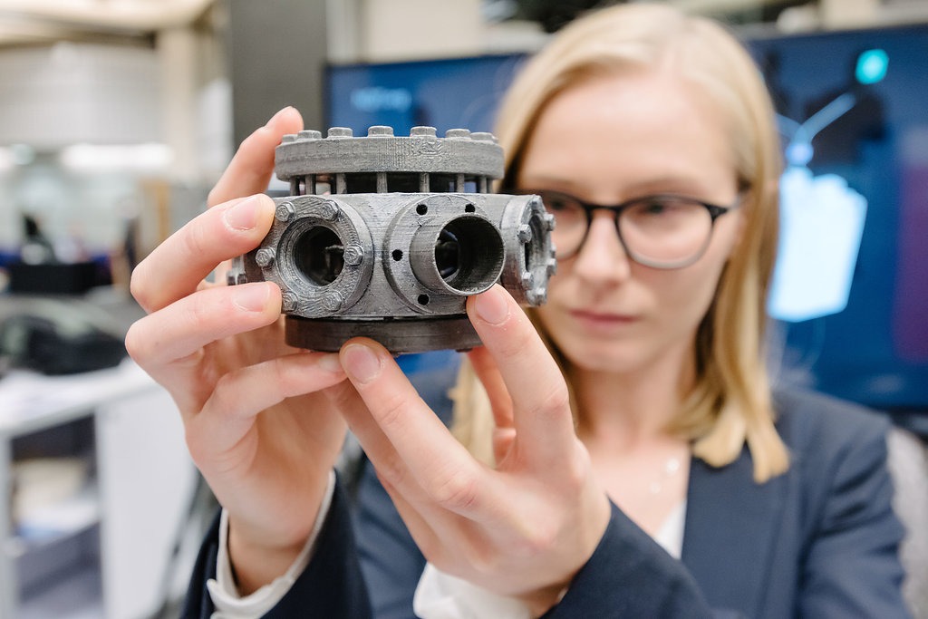 Amy Hughes holding a model of an ion trap vacuum system